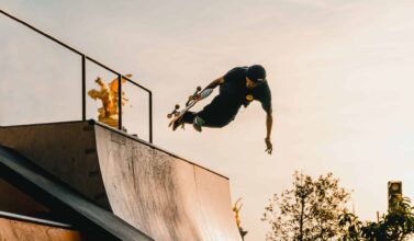 A Skateboarder gains momentum on a half-pipe as he does in aerial trick.